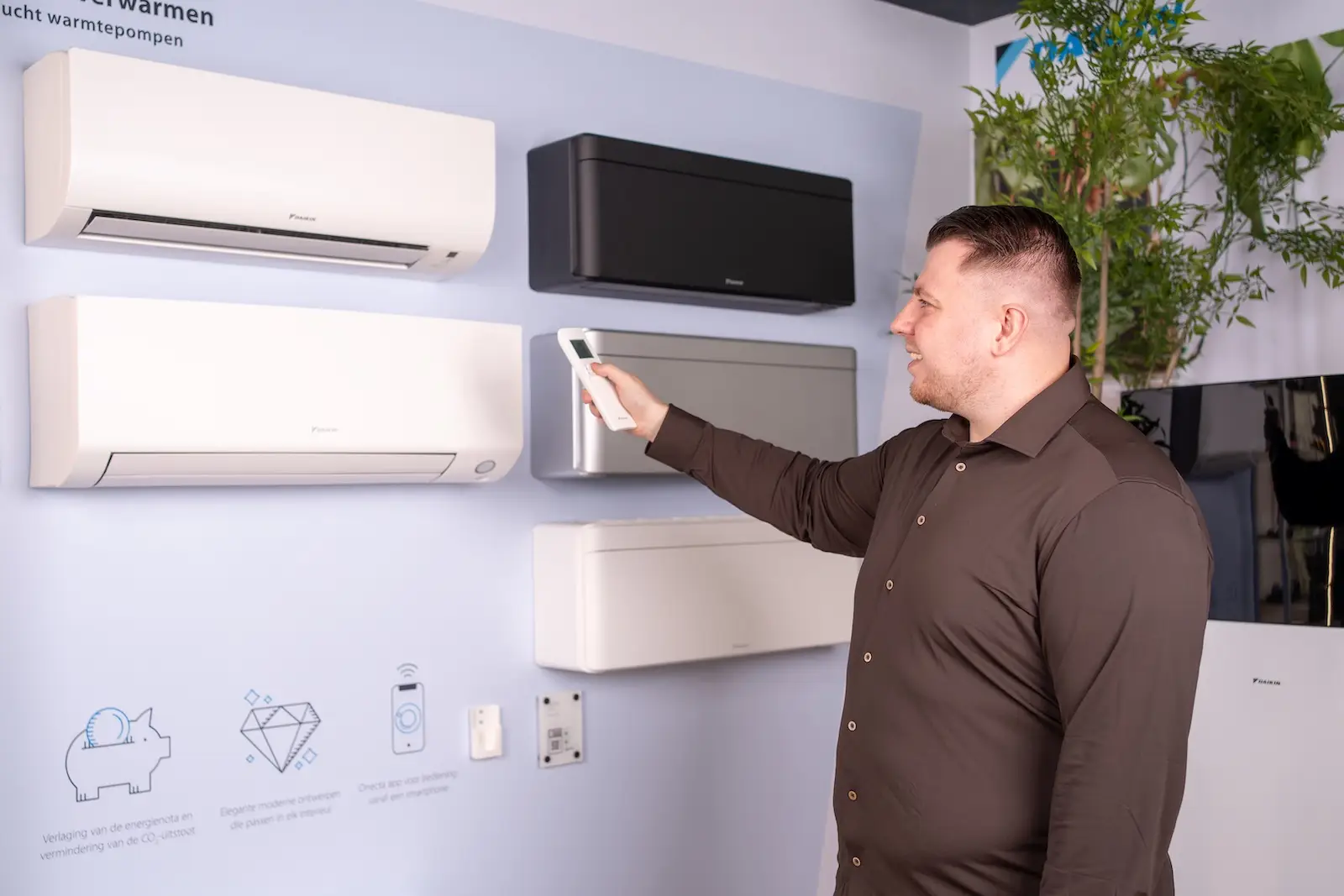 Giovanni Kokken van Jadikoel wijst naar een airco binnenunit aan de showroomwand