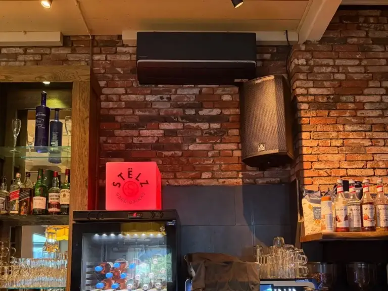 Zwarte Panasonic airco wandunit boven de bar in een restaurant in Delft, geïnstalleerd door Jadikoel
